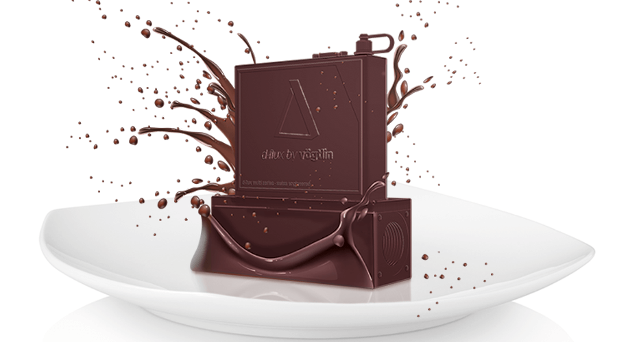 Der d-flux steht als eine illustriertes Schokoladenprodukt auf einem weissen Teller. Um ihn herum spritzen leckere Schokoladentropfen.